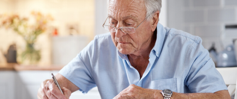 Elderly man signing papers