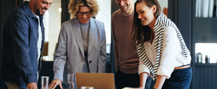 Startup owners standing around a table signing ownership agreements