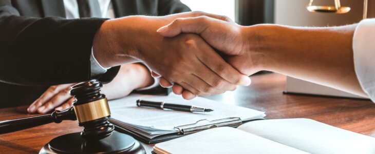 Business attorney shaking hands with client across desk