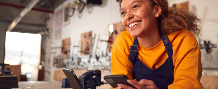 Female small business owner in orange sweater and black apron leaning over counter