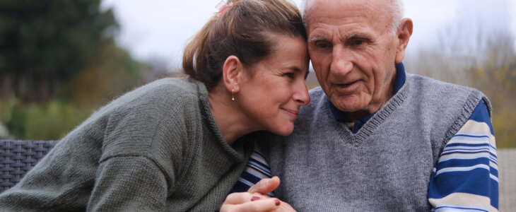 Elderly father and daughter sitting side by side