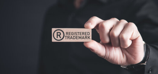 Male hand showing R-Registered trademark on wooden block.