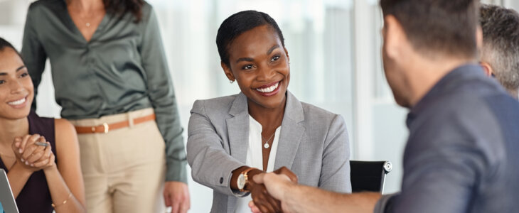 Happy black businesswoman and businessman shaking hands