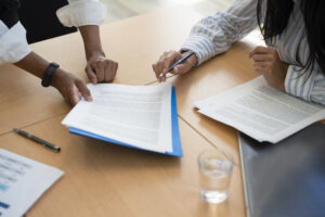 Shot of documents and female hands signing contracts