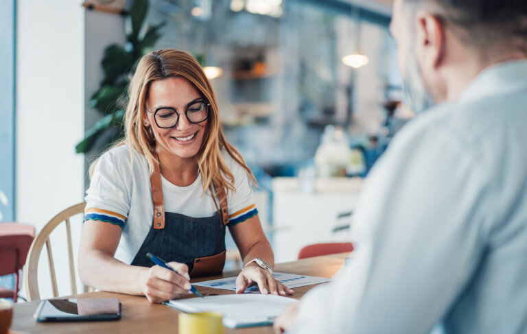 Two business persons filling in paperwork in cafeteria